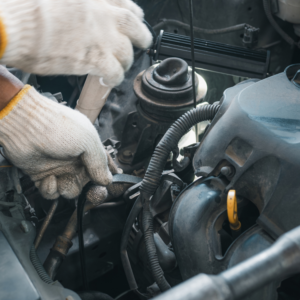 Gloved hands working on a timing belt in a car.