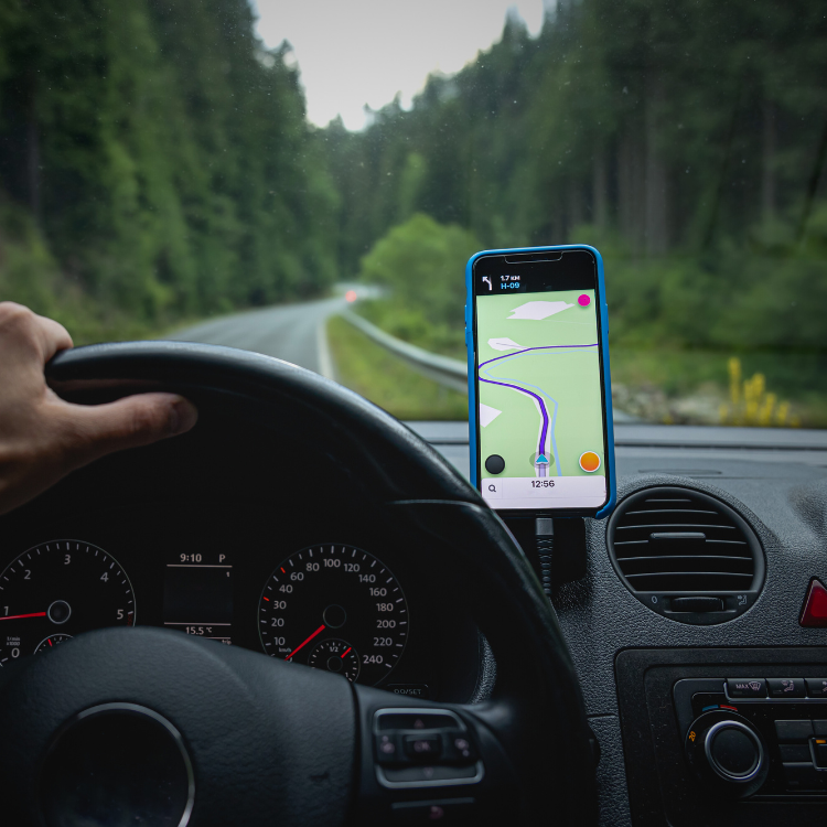 Close-up of a smart phone on a phone mount with navigation with the road through the windshield.